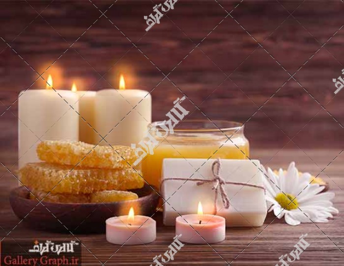 تصویر باکیفیت عسل روی میز چوبی همراه با شمع