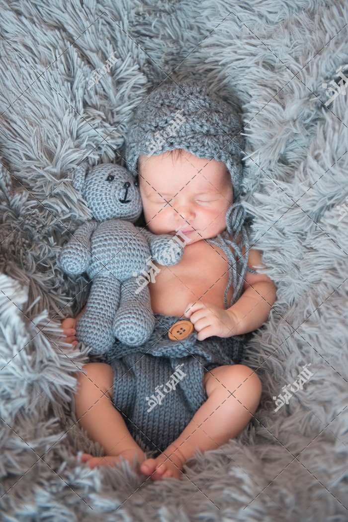 تصویر کودک نوزاد در خواب کنار عروسک خرسی