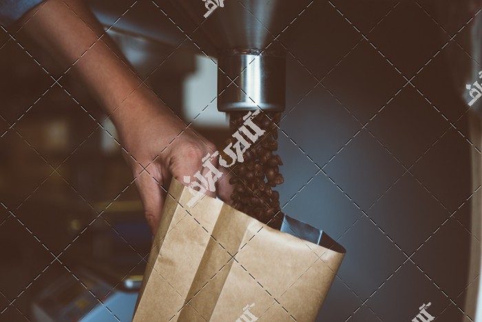 دانلود تصویر استوک با کیفیت پر کردن کیسه با دانه های قهوه