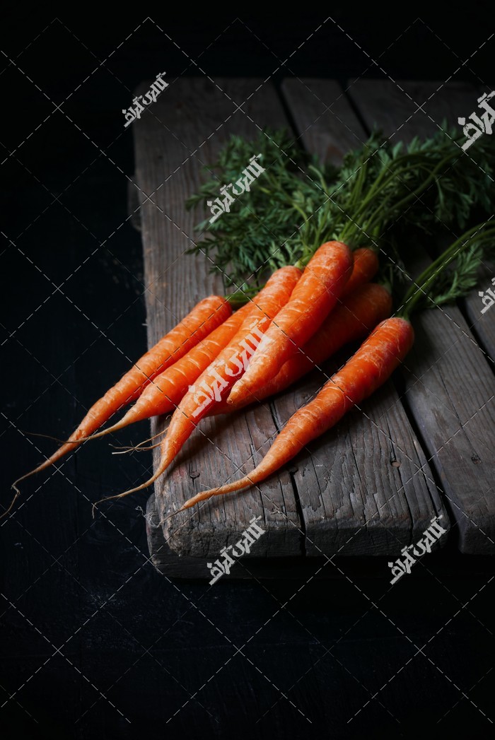 دانلود تصویر استوک با کیفیت هویج های جدا شده روی میز چوبی